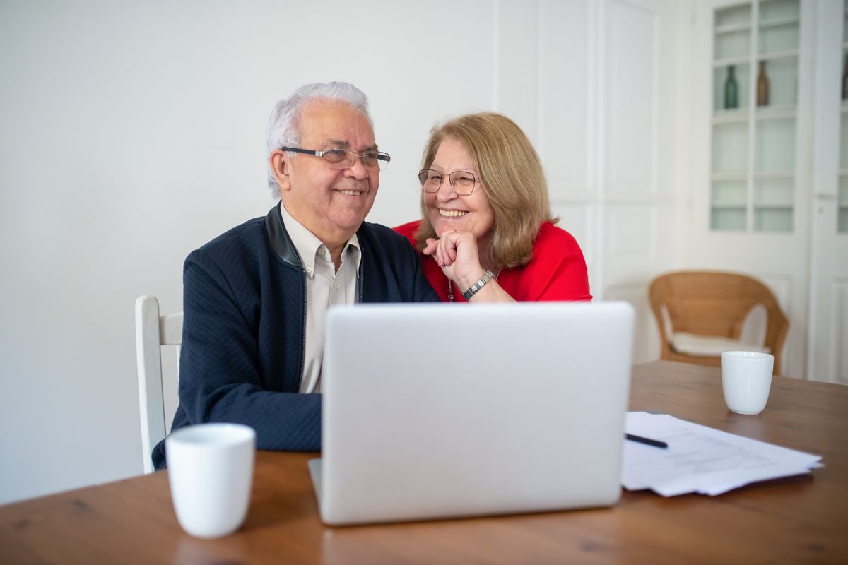 Un couple de seniors souriant devant un ordinateur portable