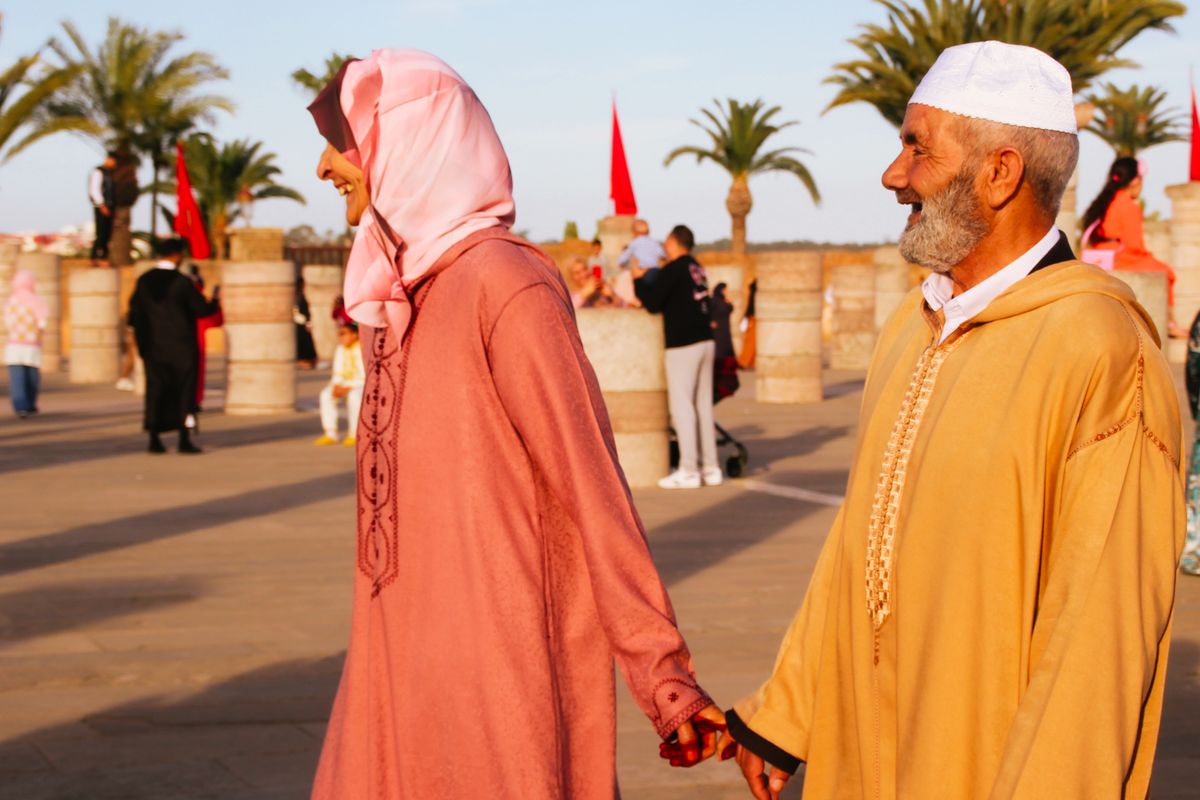 Un couple de seniors en tenue traditionnelle marocaine se tient la main