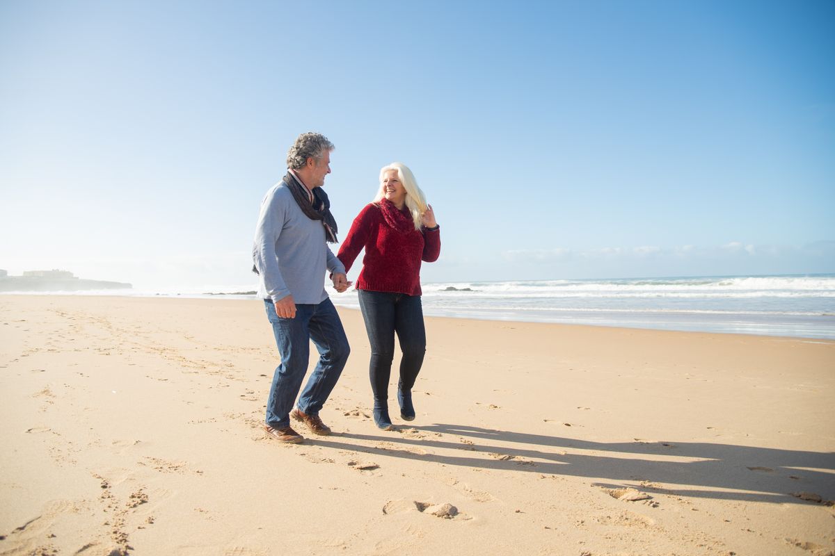 Un couple de seniors se promène sur une plage