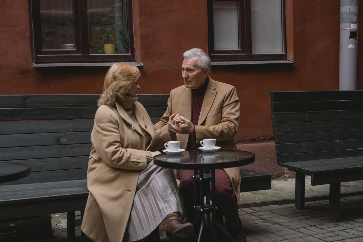 Un couple de seniors discute à la terrasse d’un café