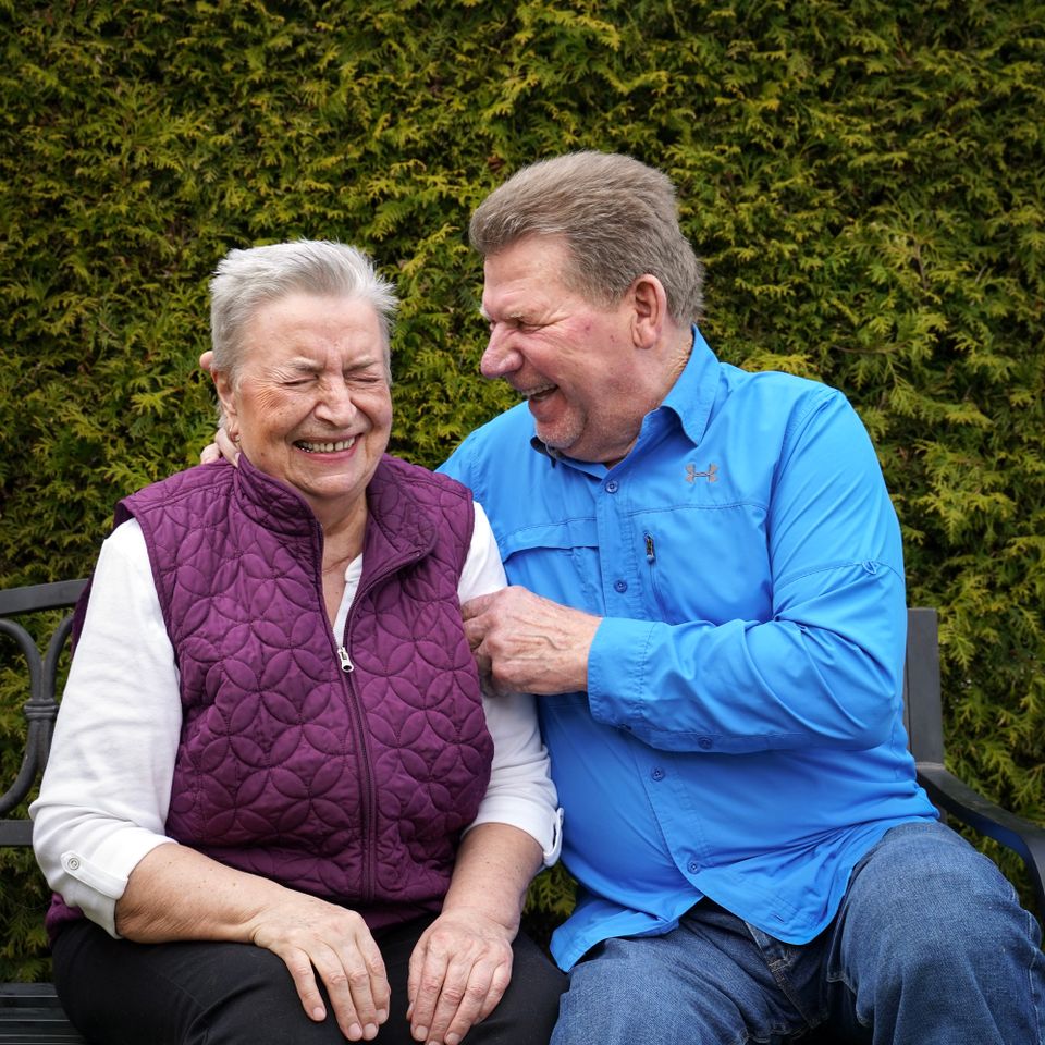 Un couple de seniors rit sur un banc